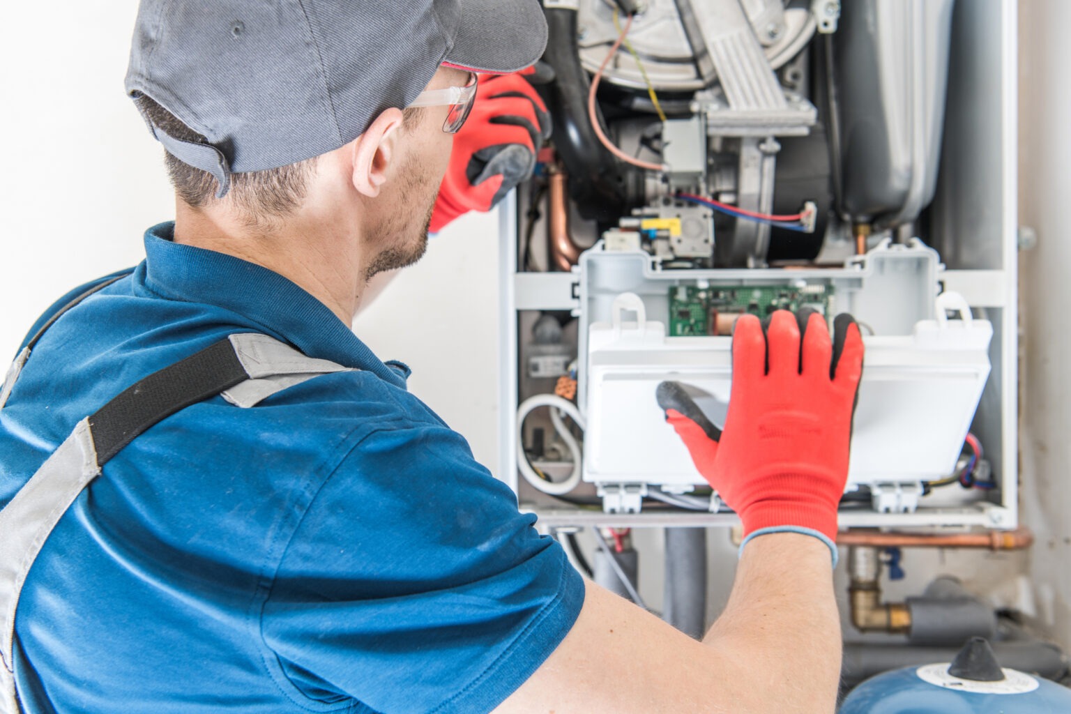 The professional is wearing red gloves and uniform while working to repair the unit.