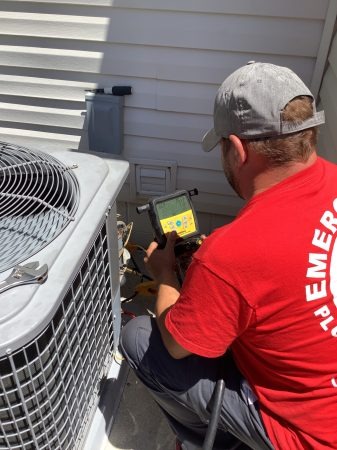 HVAC technician inspecting outside air conditioning unit.