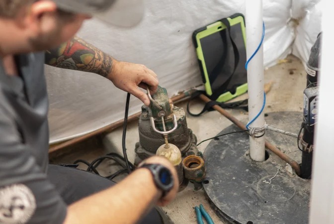 A plumber is servicing a septic system pump with a float valve.