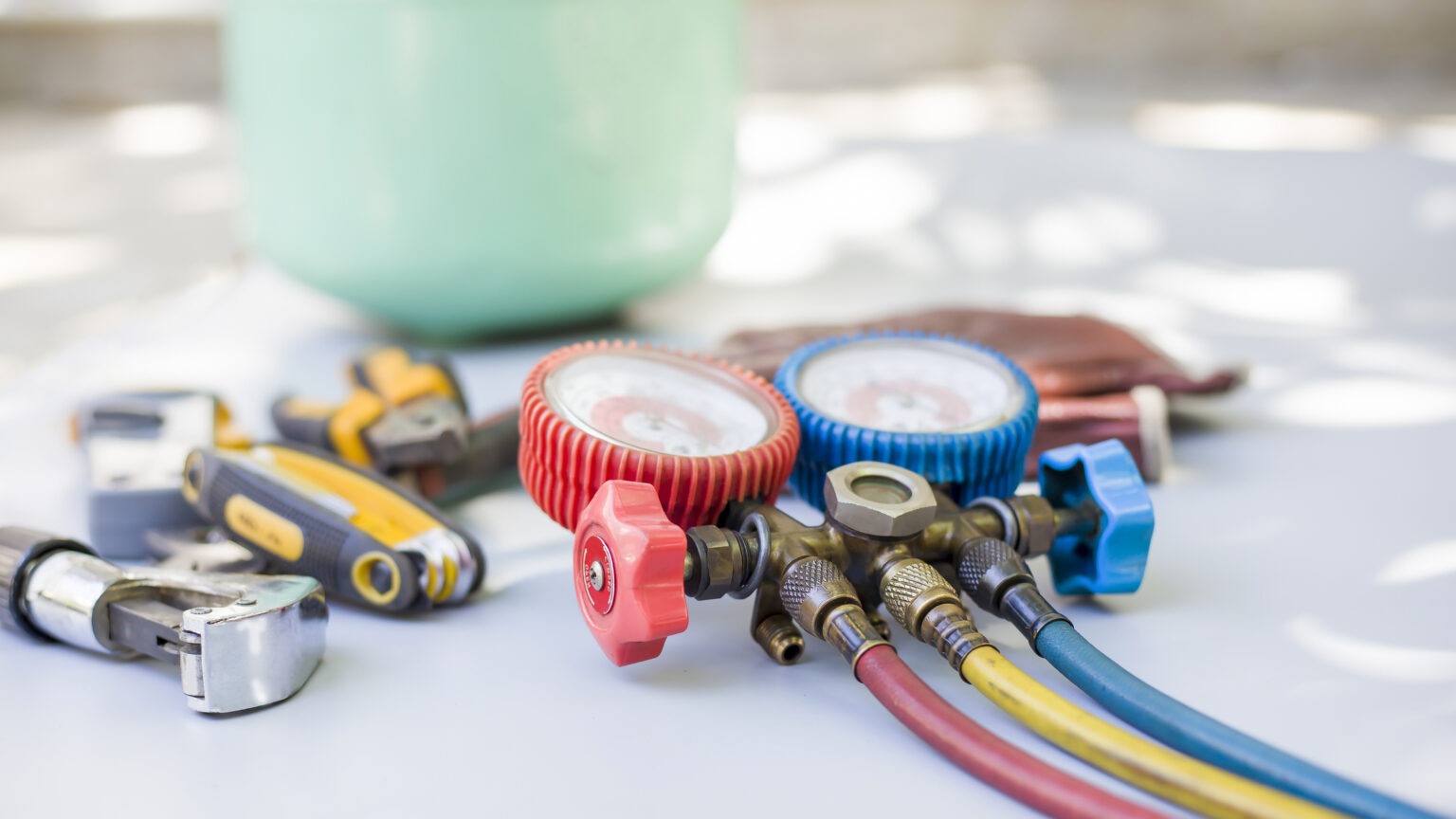 HVAC service tools, including a manifold gauge set with red, blue and yellow hoses.