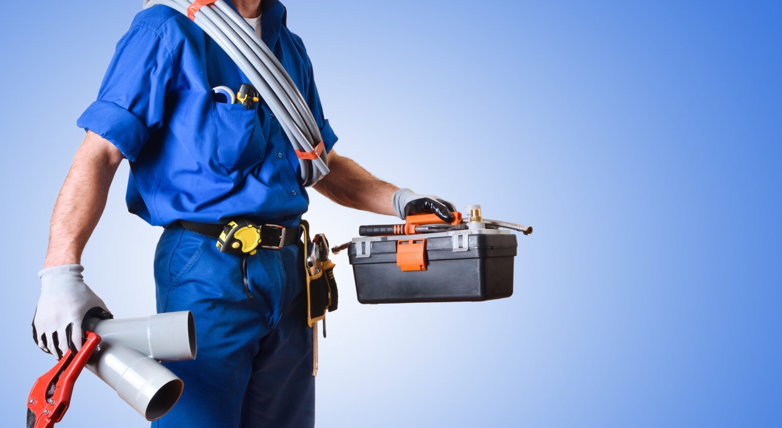 A plumber holds plumbing tools, a toolbox, and PVC pipes.