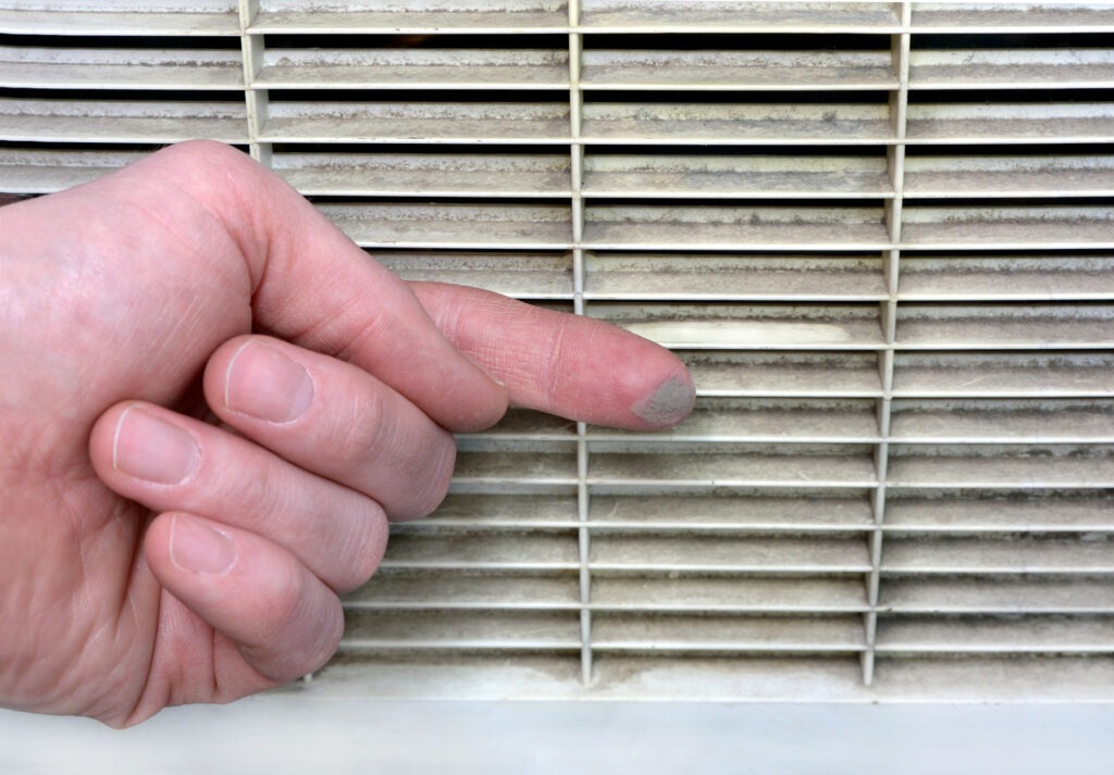 A finger wipes dust from an air vent, showing how air filters can get dirty.