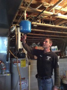 A plumber inspects a water system component in a basement